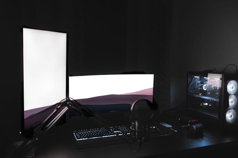 A glowing dual-monitor 3D workstation setup in a dark room